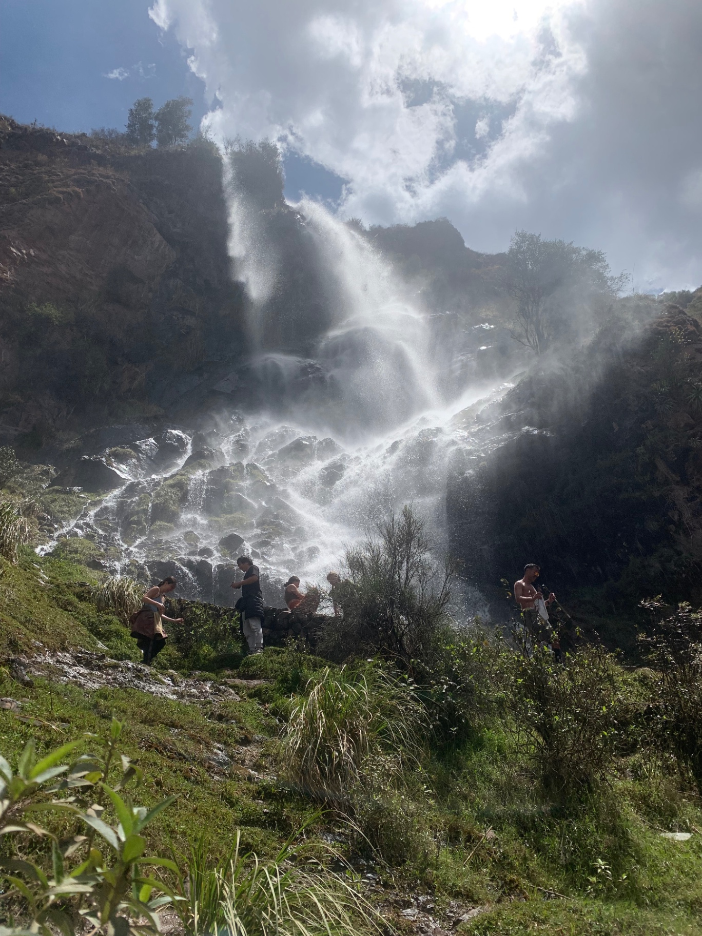 A wide misty waterfall pouring down the Andean hillside