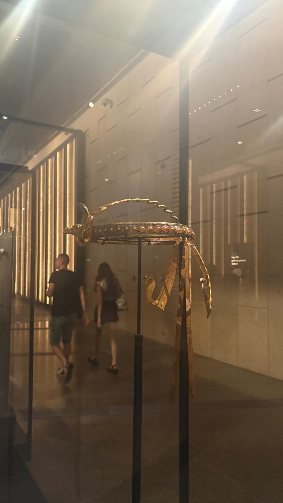 Visitors walking through a dim gallery of gold jewellery cases