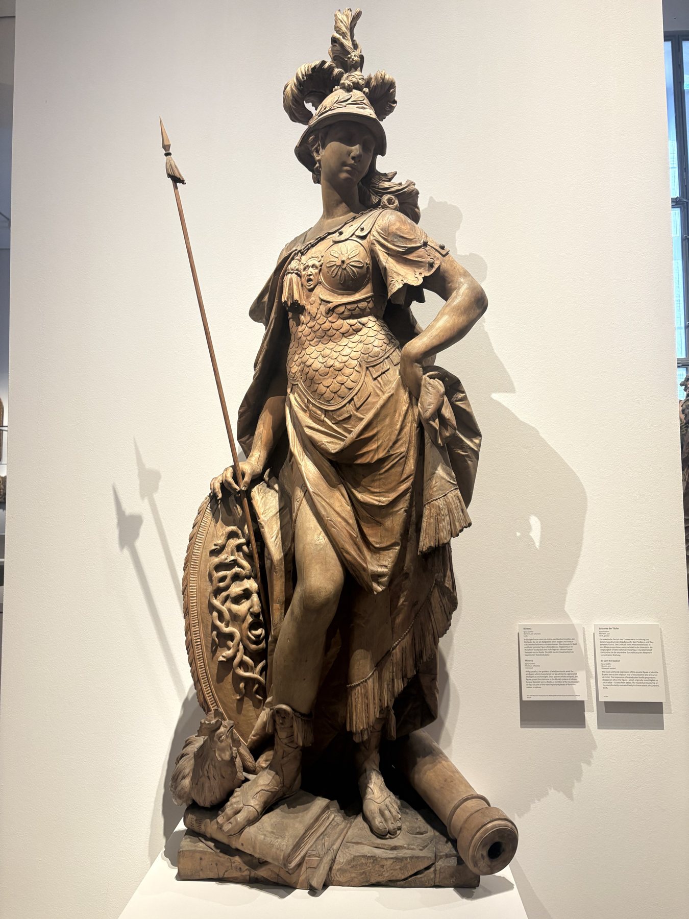 A bronze armoured Minerva figure with spear and helmet in a museum gallery