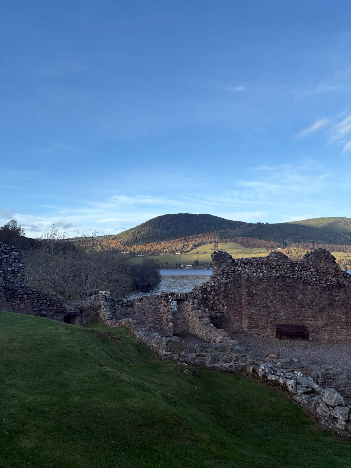 Stone walls of Urquhart Castle with autumn hills and the loch beyond