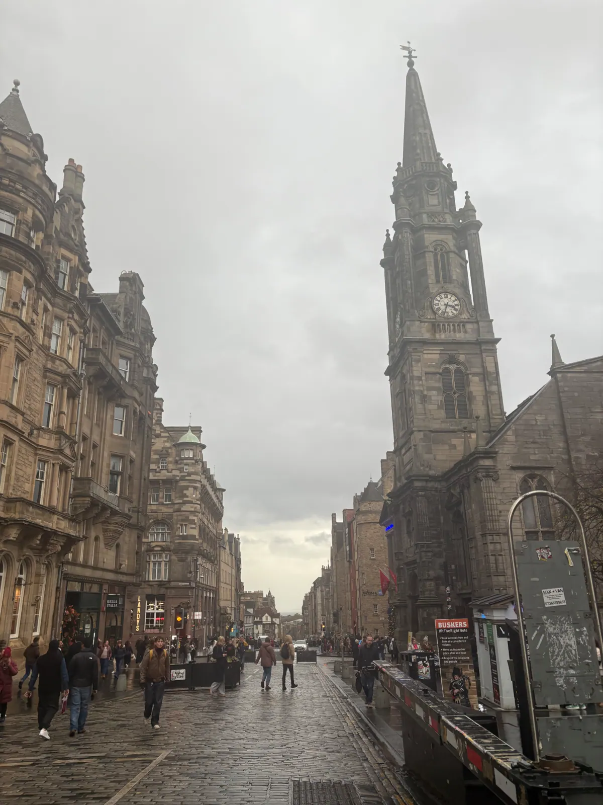 The Tron Kirk spire above wet cobbles on the Royal Mile under grey cloud