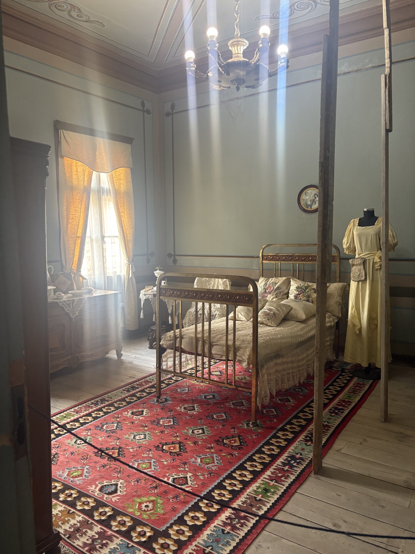A preserved bedroom with a dress hanging beside the bed
