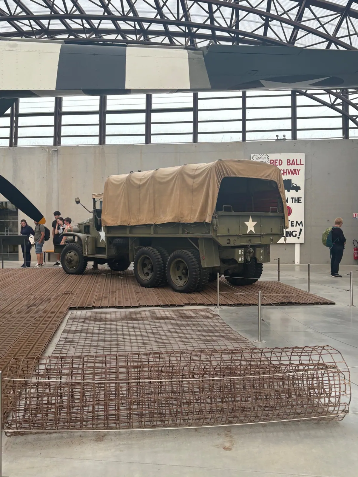 A restored US Army truck beside a Red Ball Highway sign inside the Utah Beach museum hangar