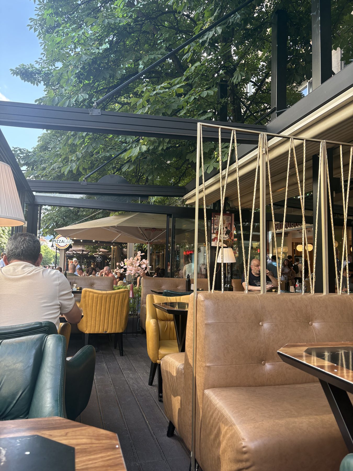 A sunlit cafe interior with green banquettes in Sofia