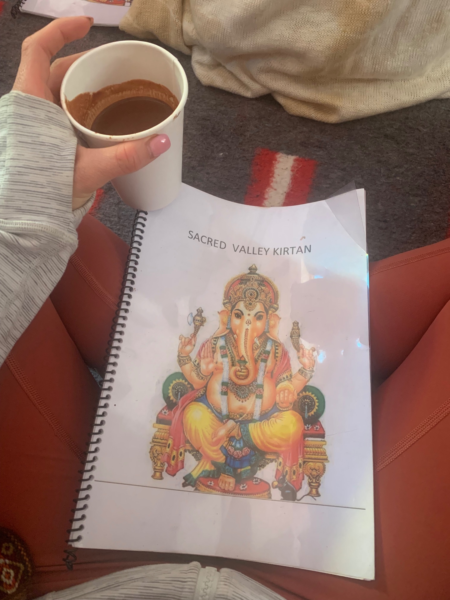 Cup of ceremonial cacao resting on a Sacred Valley kirtan songbook