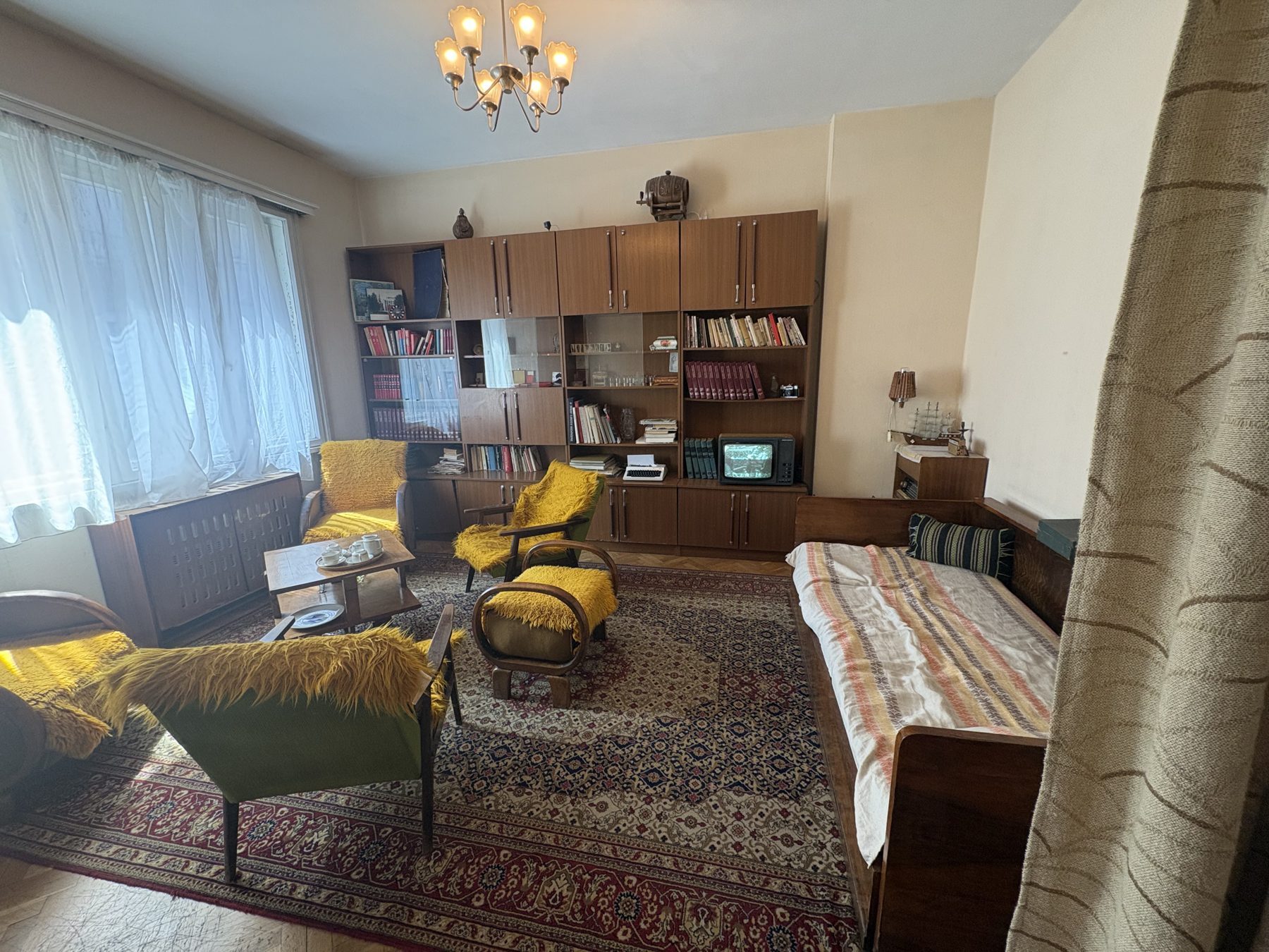 A preserved socialist-era living room with yellow chairs and bookshelves