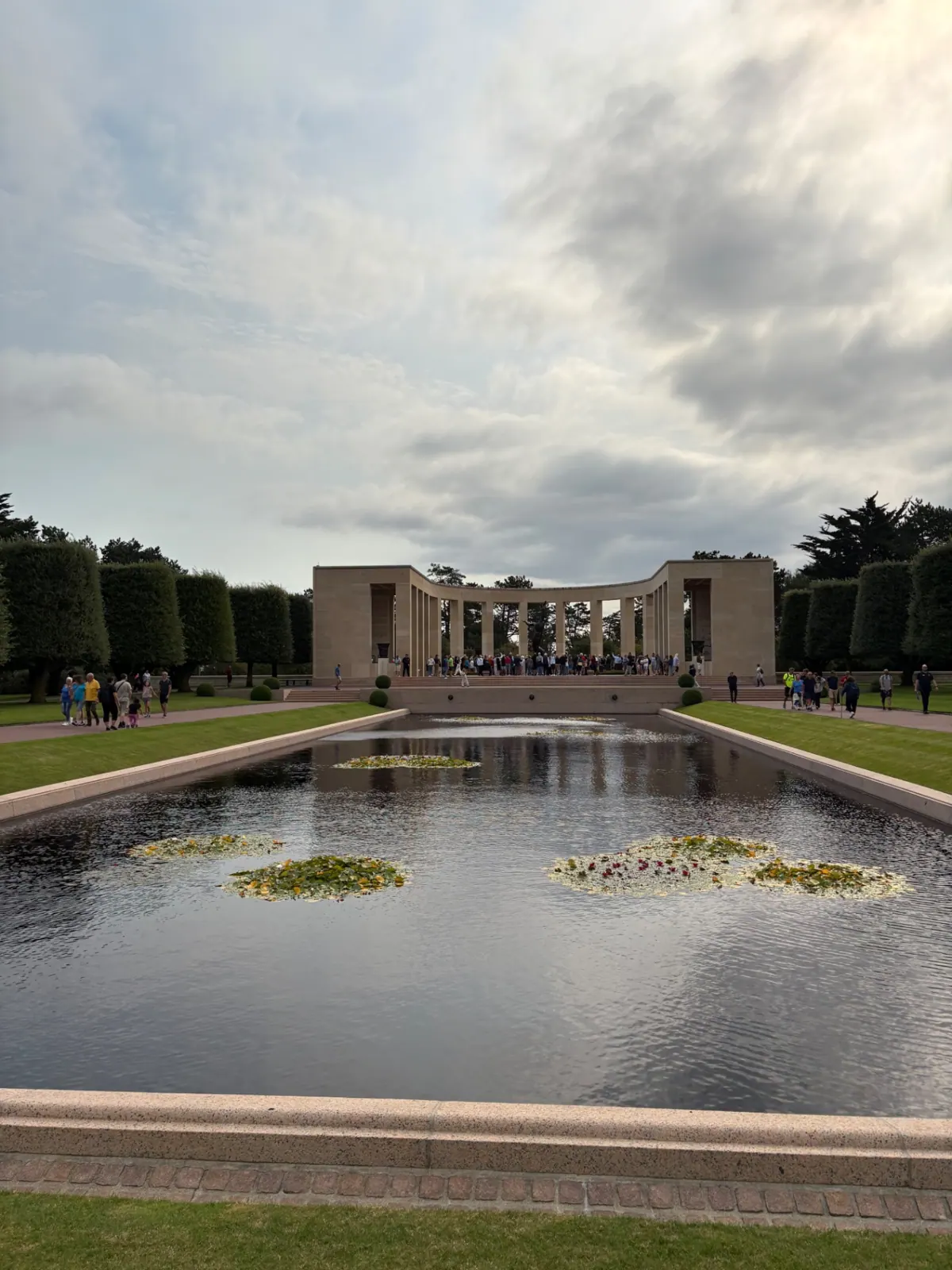 The memorial colonnade at the Normandy American Cemetery under a wide bank of grey cloud