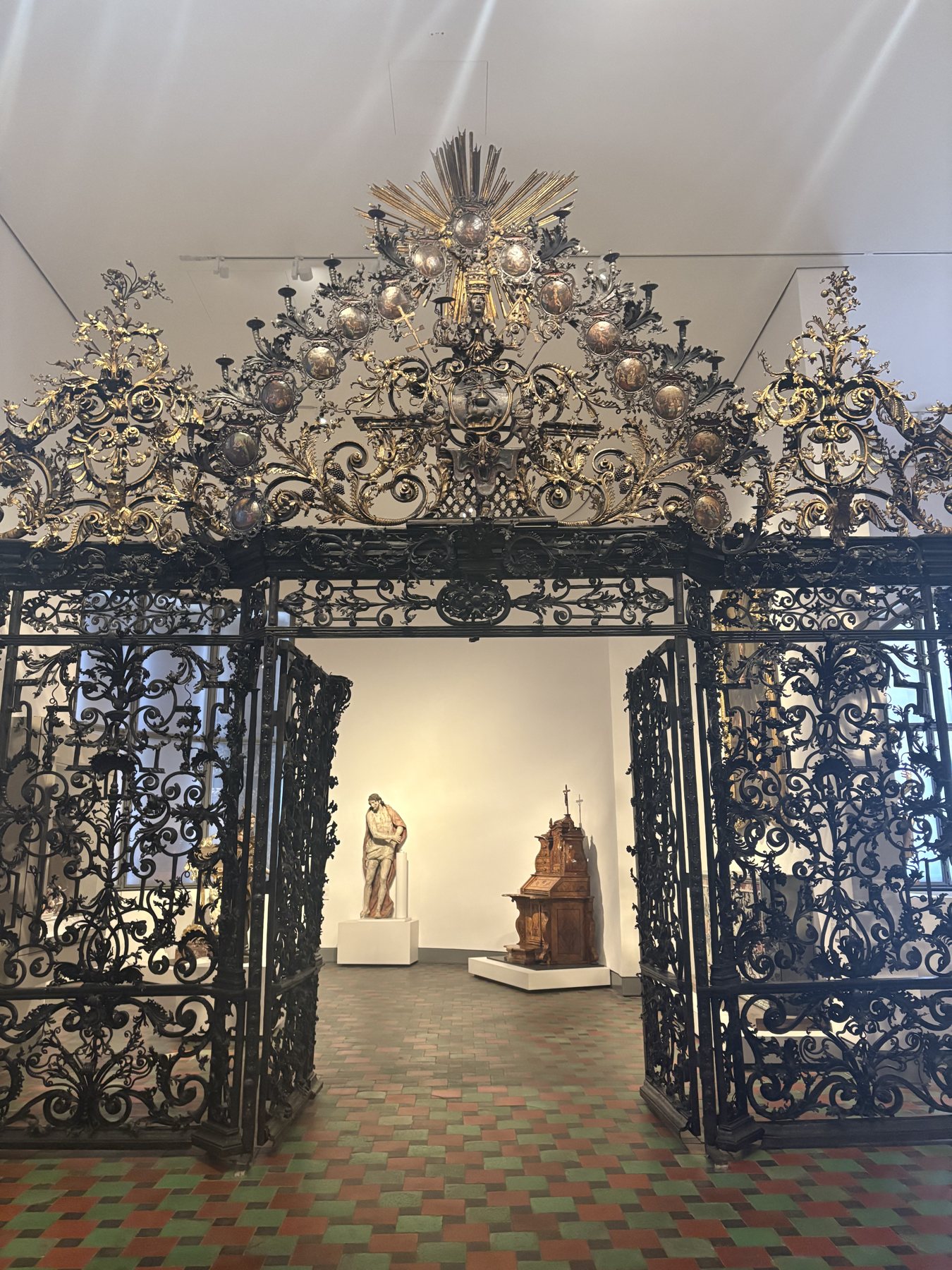 An ornate wrought iron gate displayed inside the Bavarian National Museum