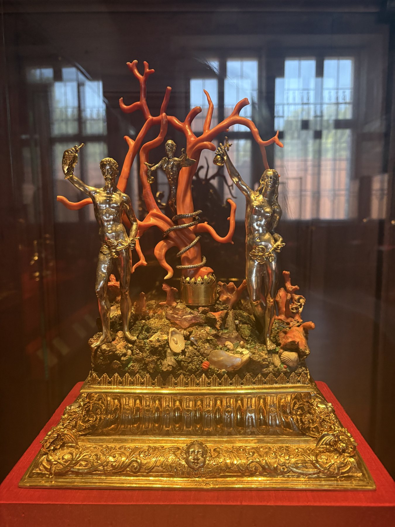 A gilded shrine set with red coral branches and small figures