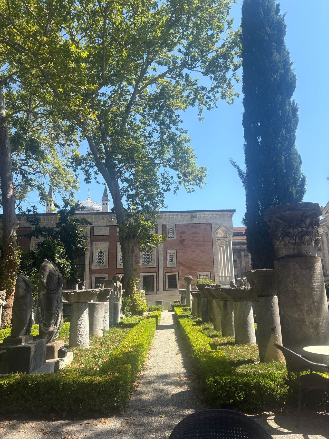 A museum garden lined with cypress trees and statues