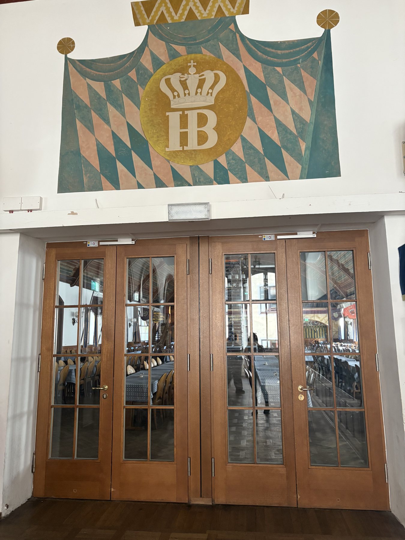 The Hofbräuhaus doors under a painted Bavarian diamond crest