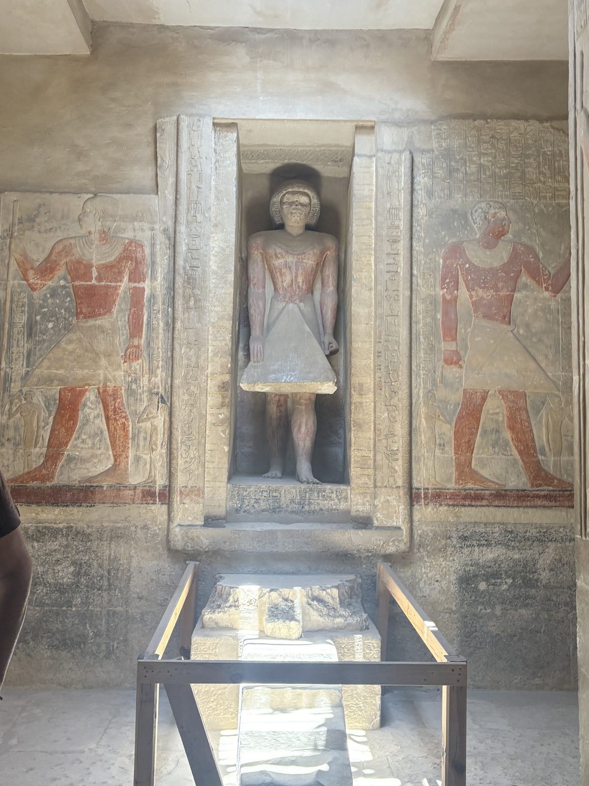 A statue standing in a painted niche inside an ancient Egyptian tomb