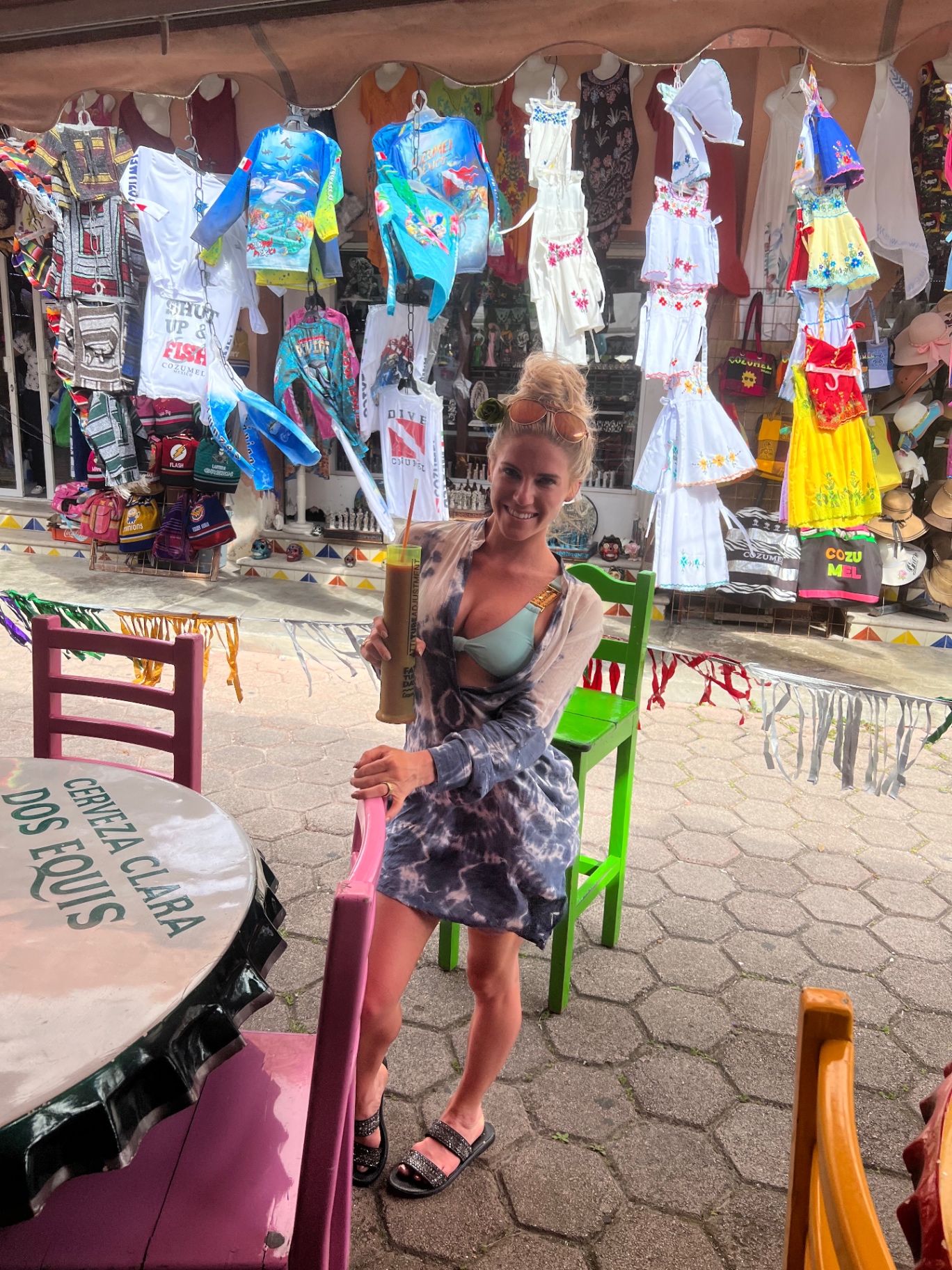 Posing with a tall drink outside a colorful Cozumel market stall