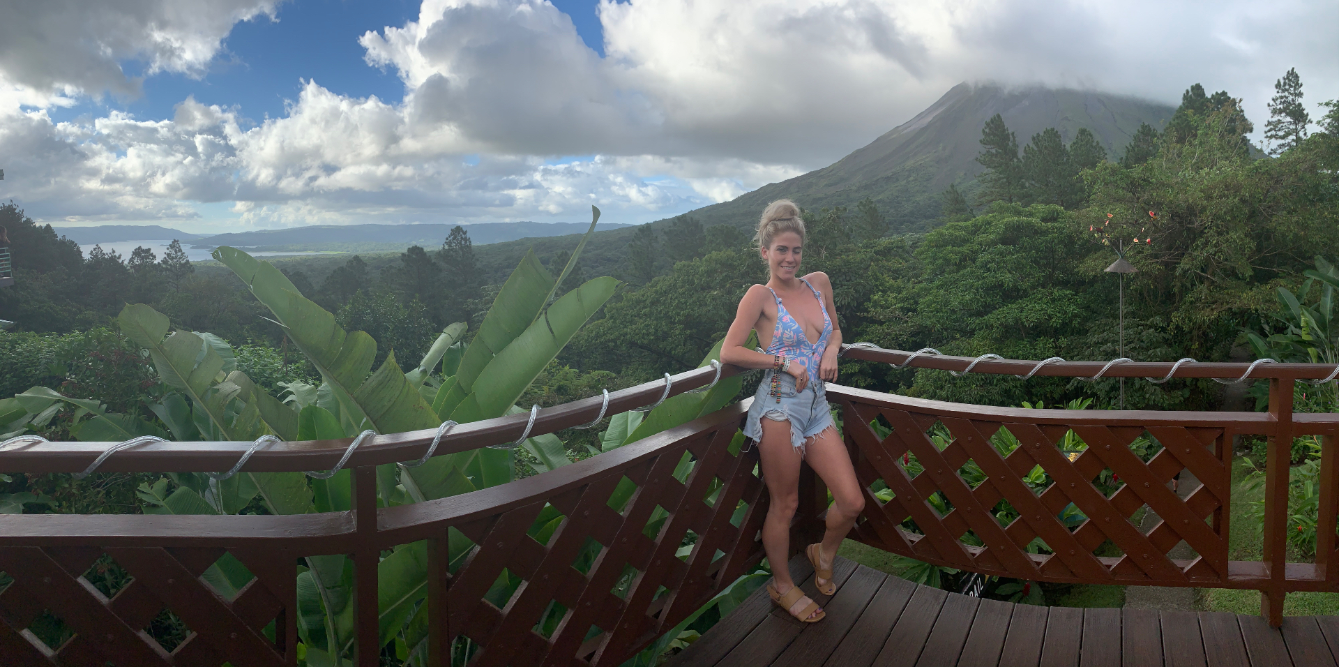 Standing on a wooden deck with Arenal volcano and the rainforest behind