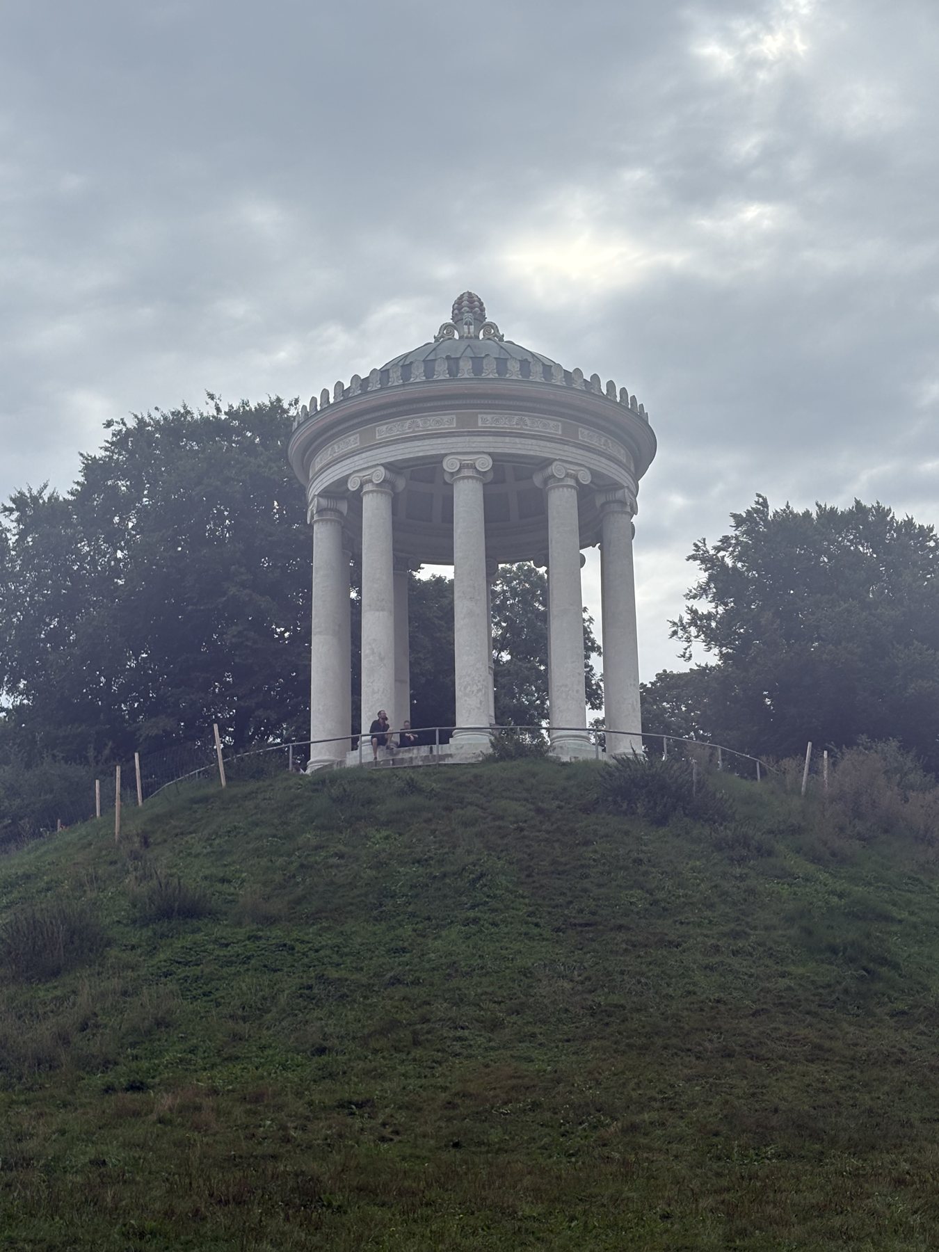 The Monopteros temple on its hill in the English Garden under grey cloud