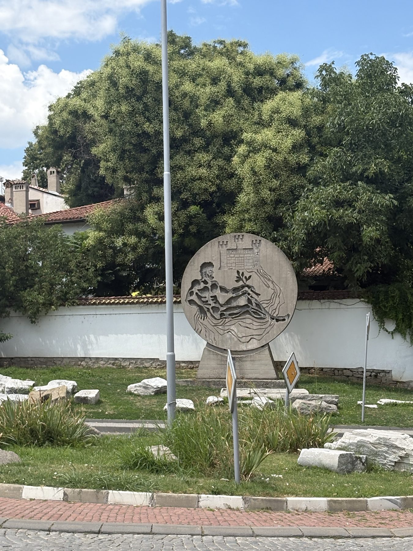 A circular stone relief monument in a garden of ruins