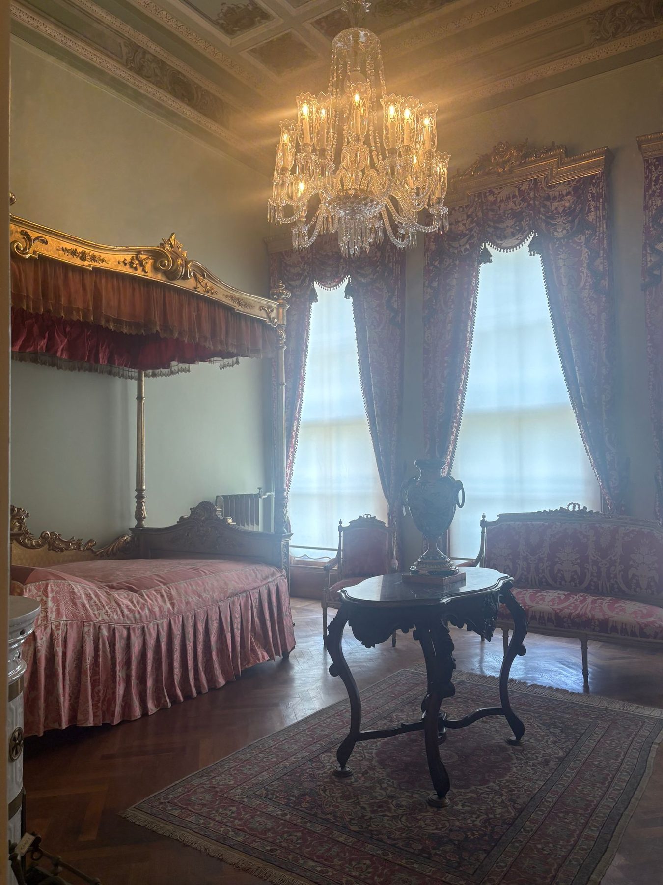 An ornate palace bedroom with lace curtains and chandelier