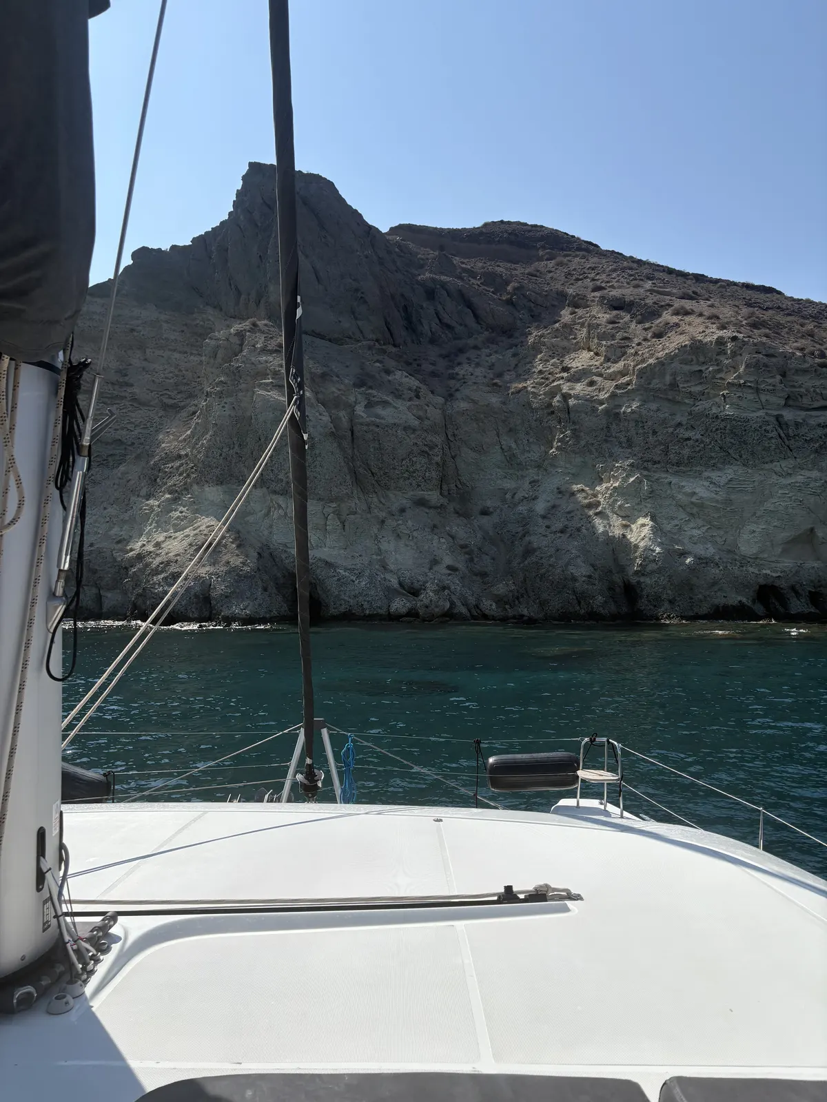 Sailing beneath the volcanic cliffs of Santorini by catamaran