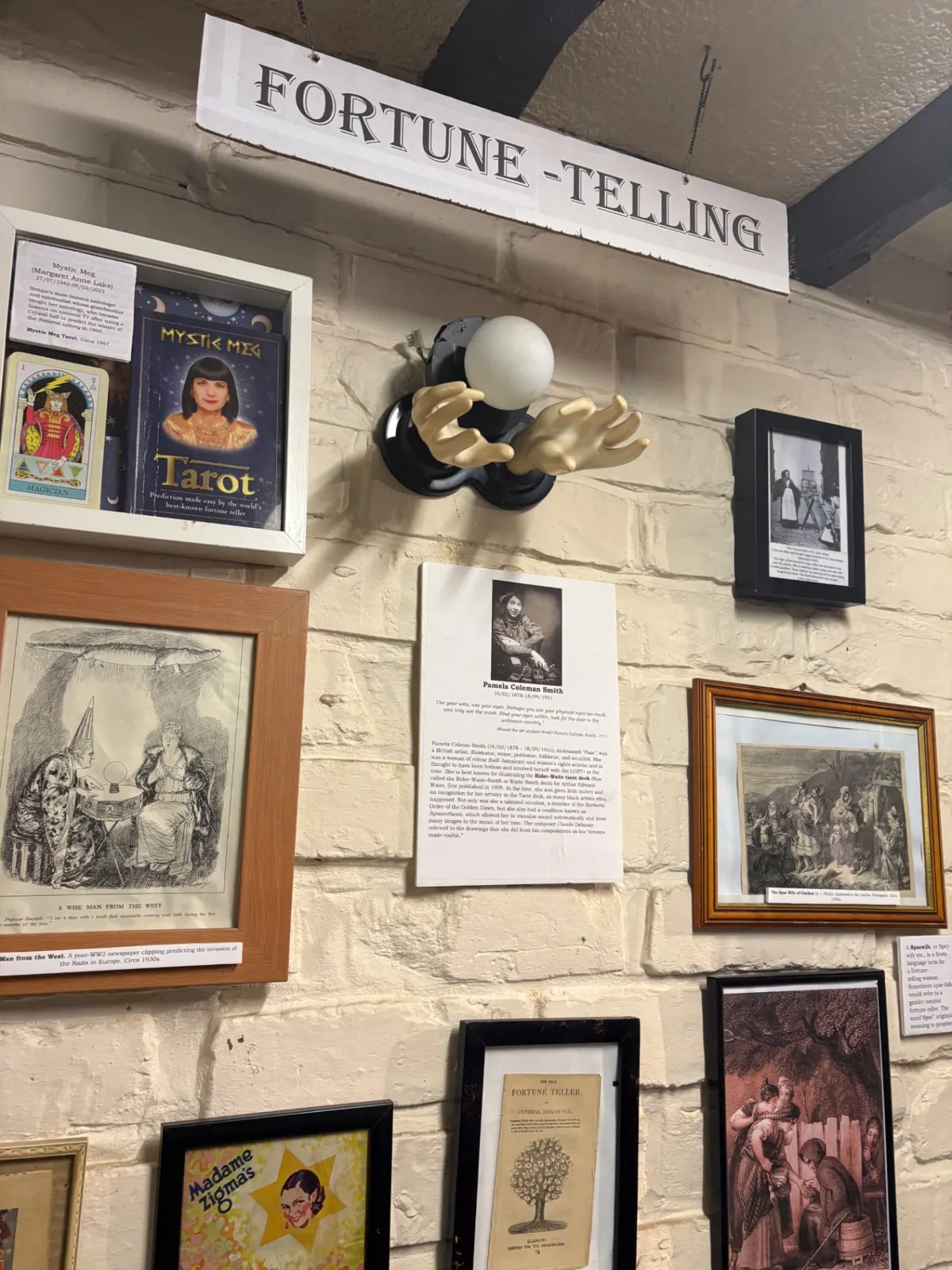 A museum wall of fortune-telling history including Mystic Meg and Pamela Colman Smith