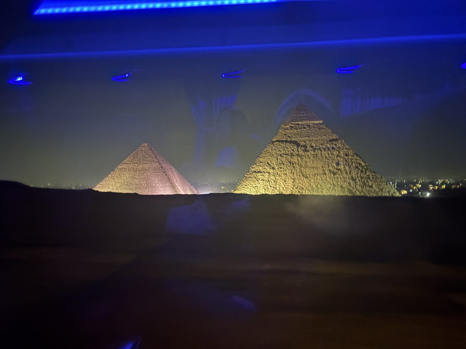 The pyramids of Giza lit at night against a black sky
