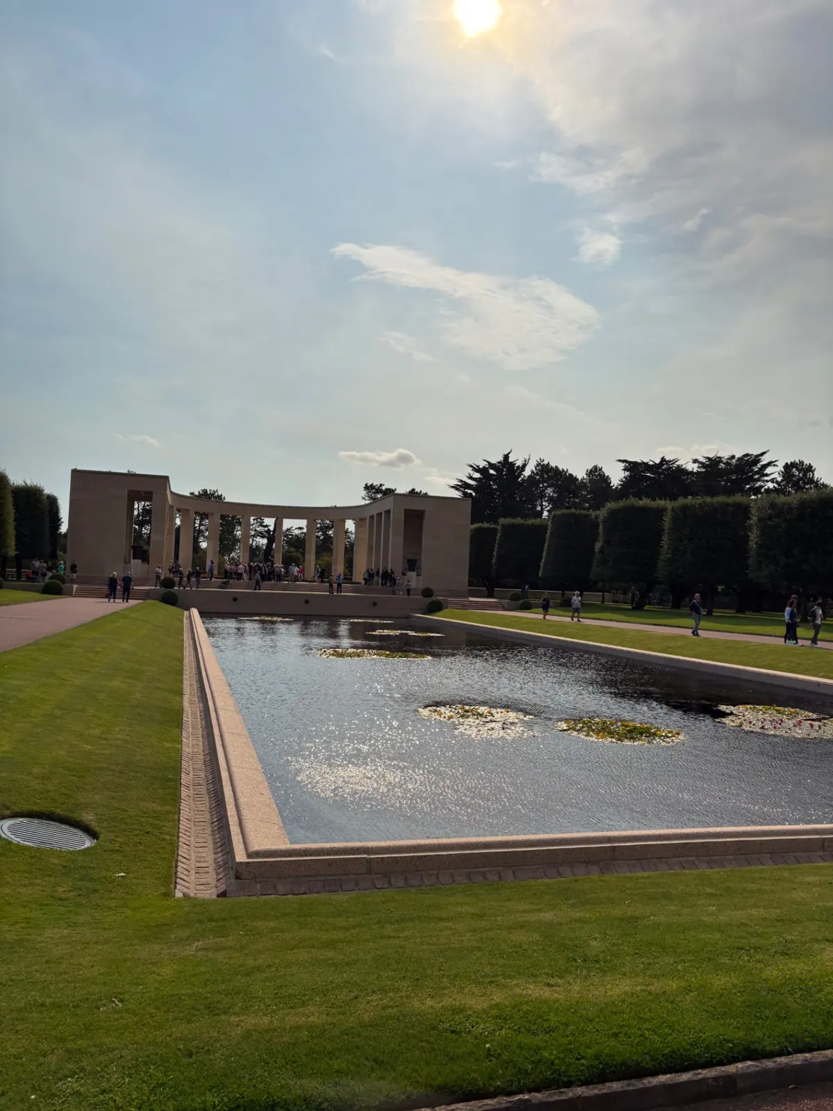 Sunlight glittering on the reflecting pool in front of the memorial colonnade at Colleville-sur-Mer
