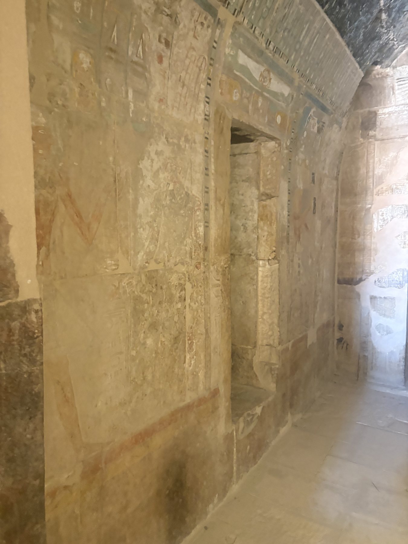 A sunlit stone corridor with hieroglyphs