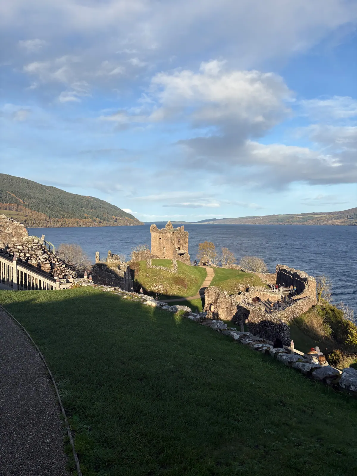 Urquhart Castle ruins on a green headland above the deep blue of Loch Ness