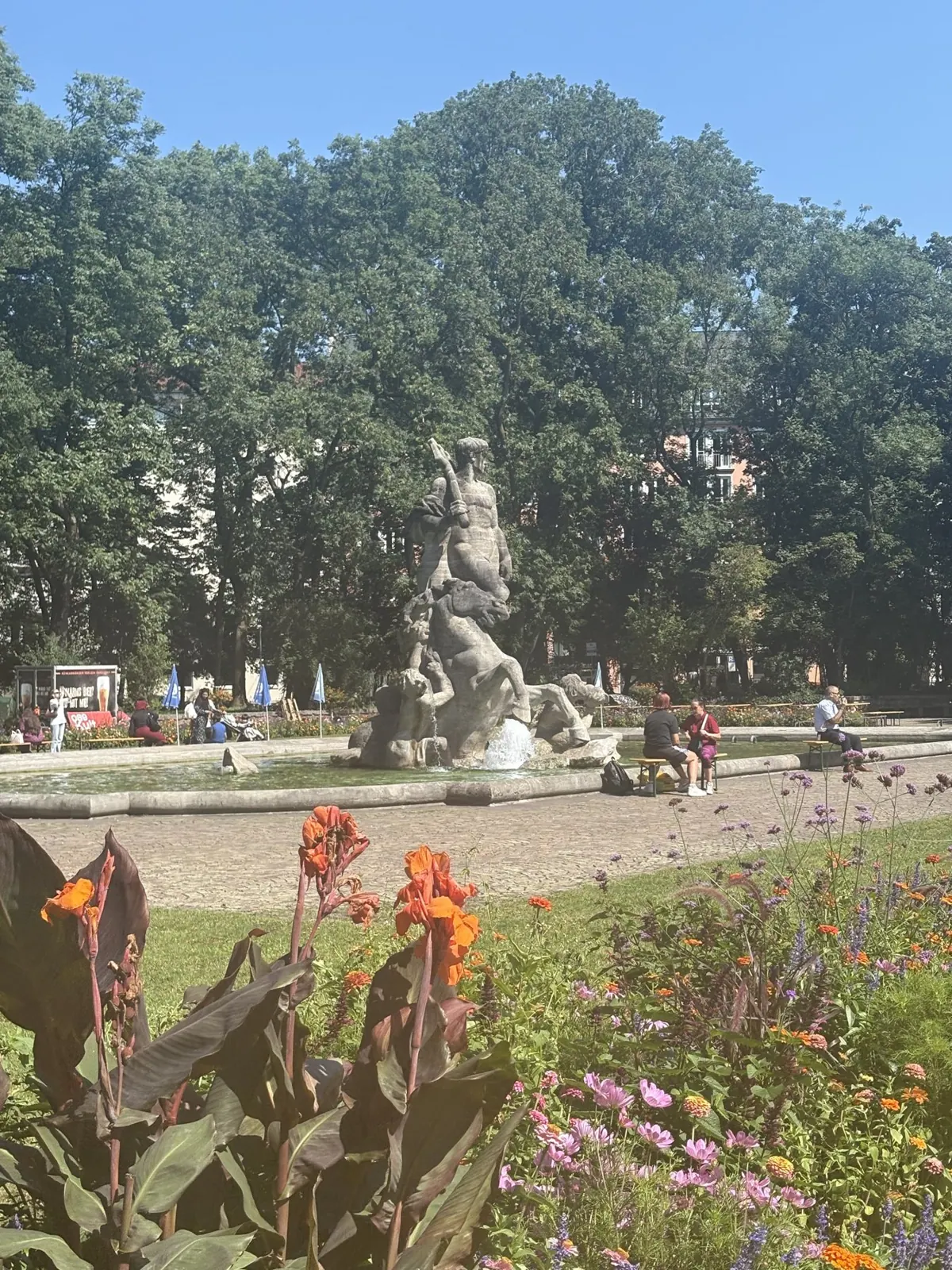 A stone statue among flowering beds in a Munich park