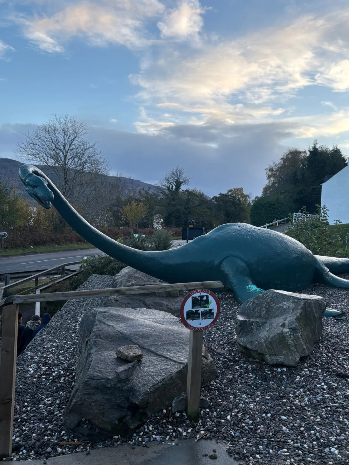 A green Loch Ness monster sculpture beside the road at the Clansman Hotel