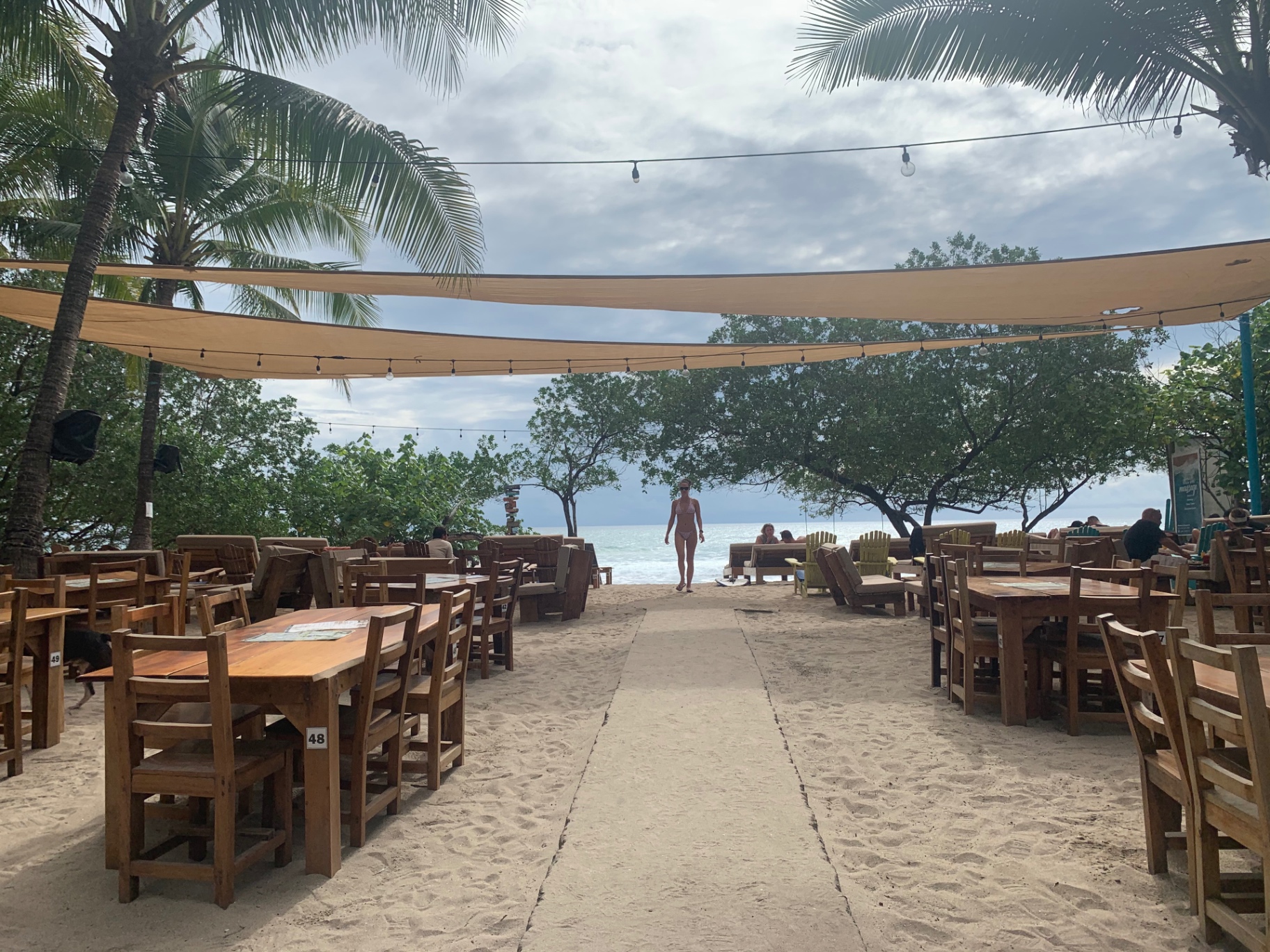 Beachfront tables under sail shades looking out to the Pacific