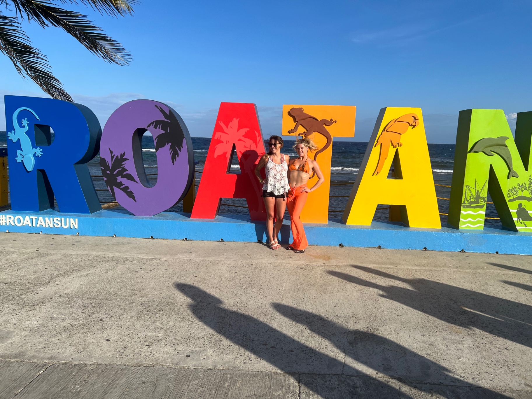 Posing with a friend in front of the colorful ROATAN letters by the water