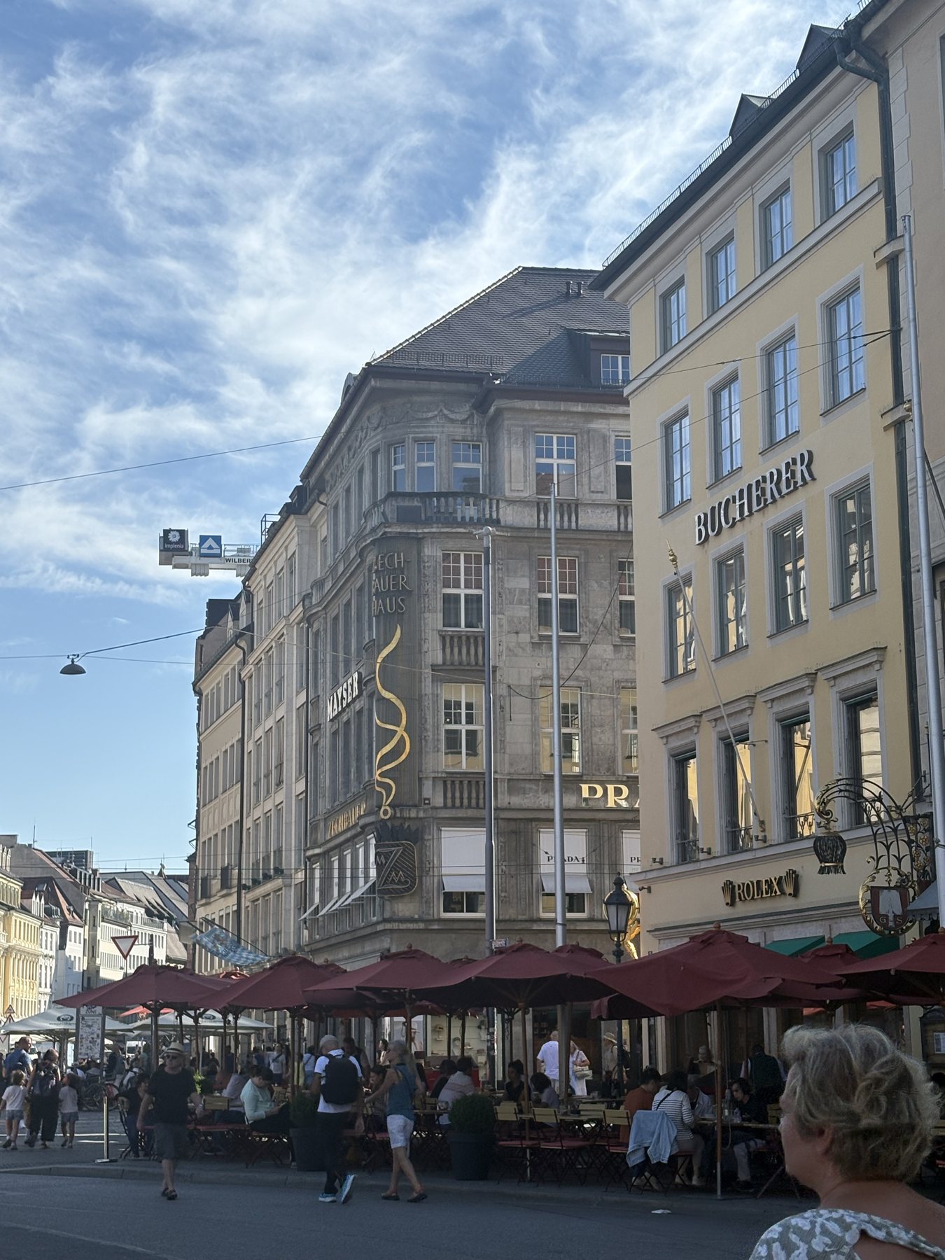 Cafés with red awnings on a Munich square busy with people