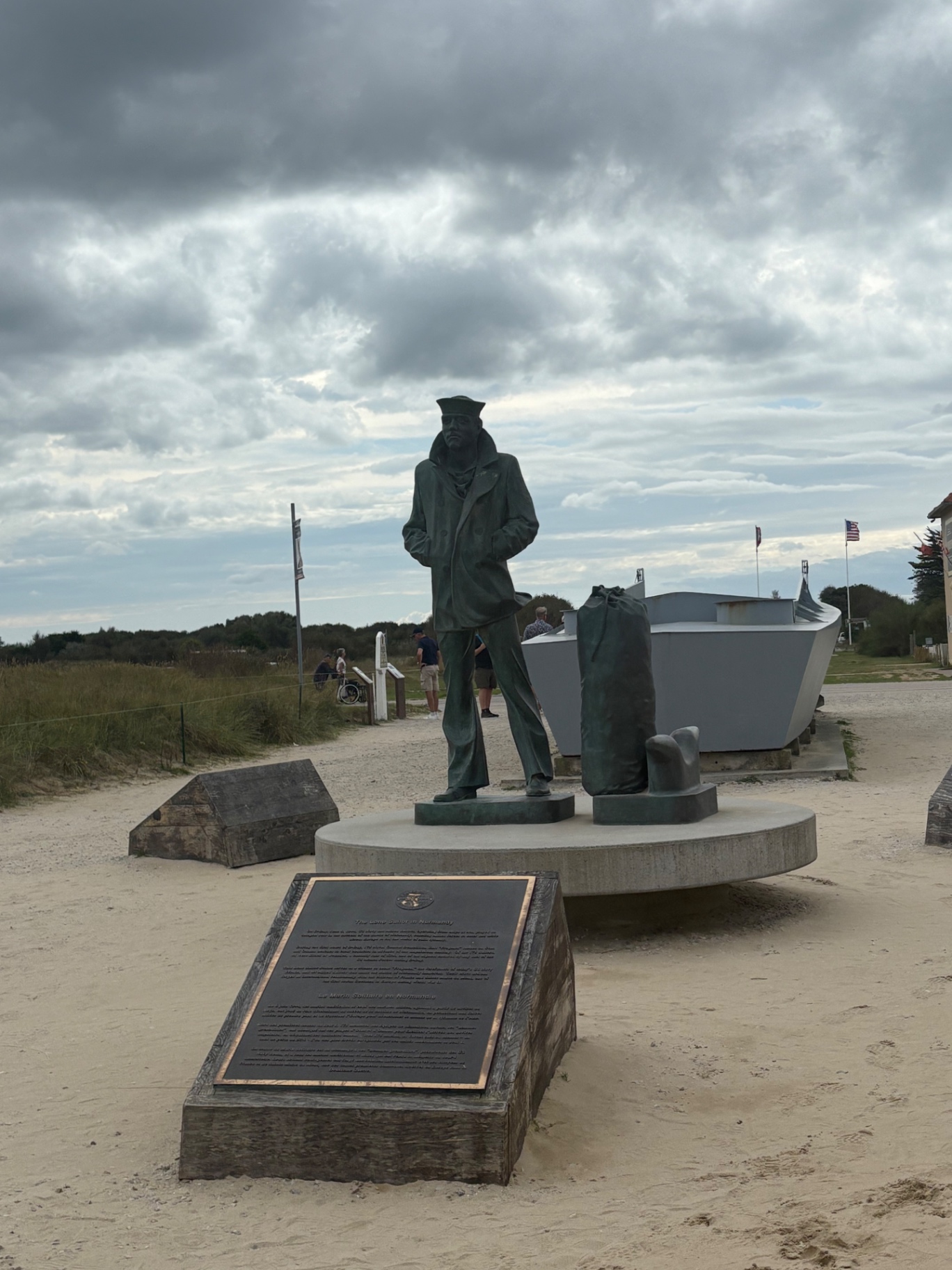 The Lone Sailor statue standing on sand beside a landing craft at Utah Beach