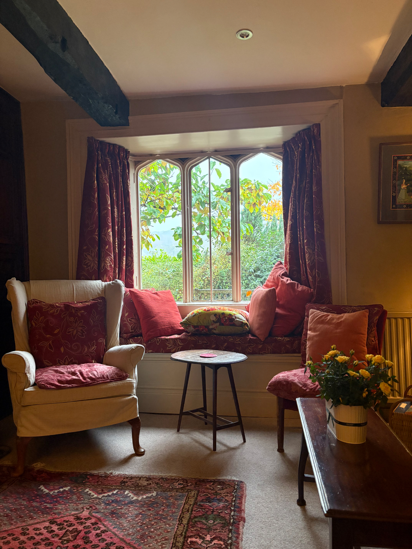 A window seat with red cushions in the cottage sitting room