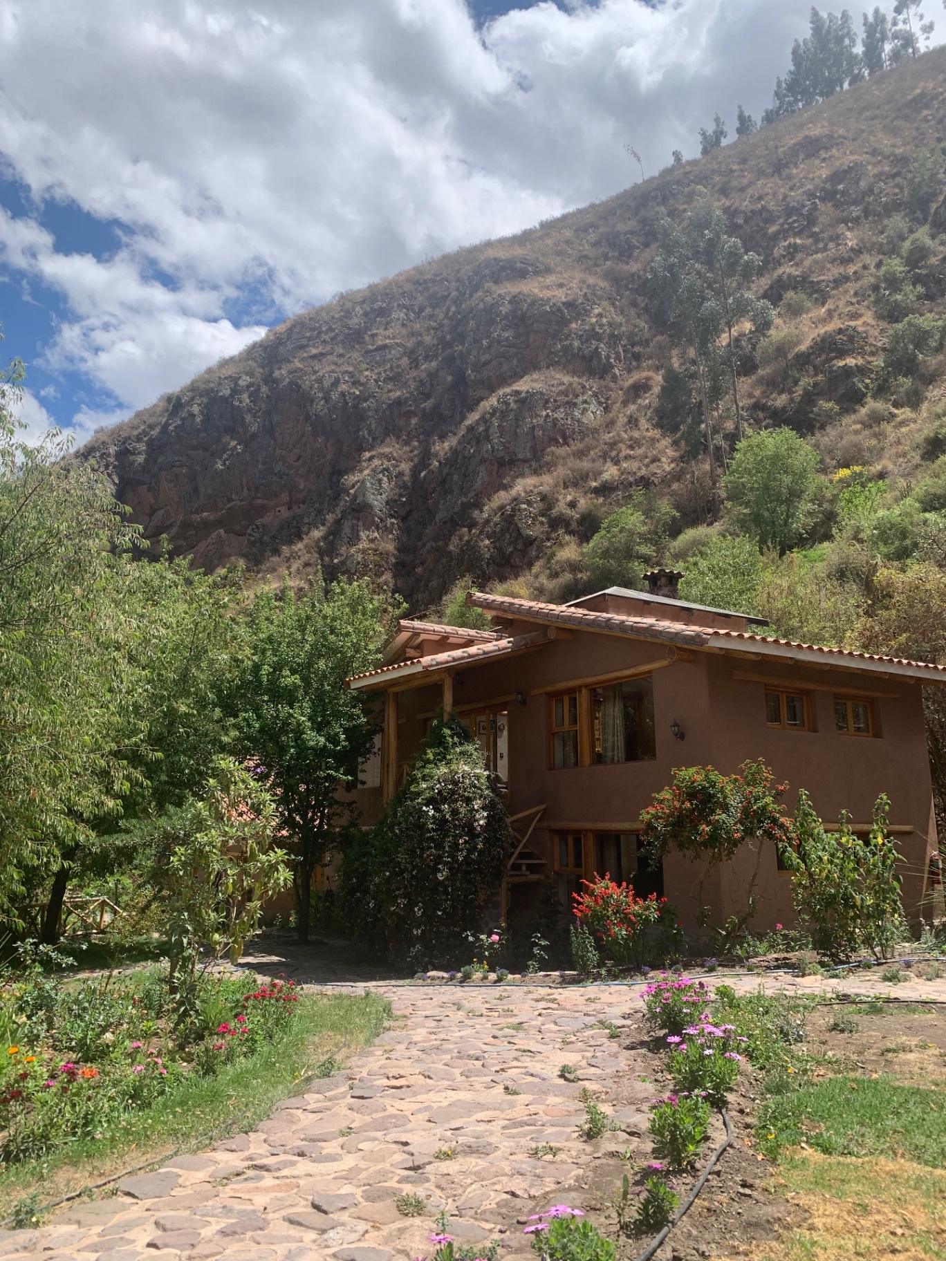Adobe retreat house with a tiled roof beneath a Sacred Valley hillside