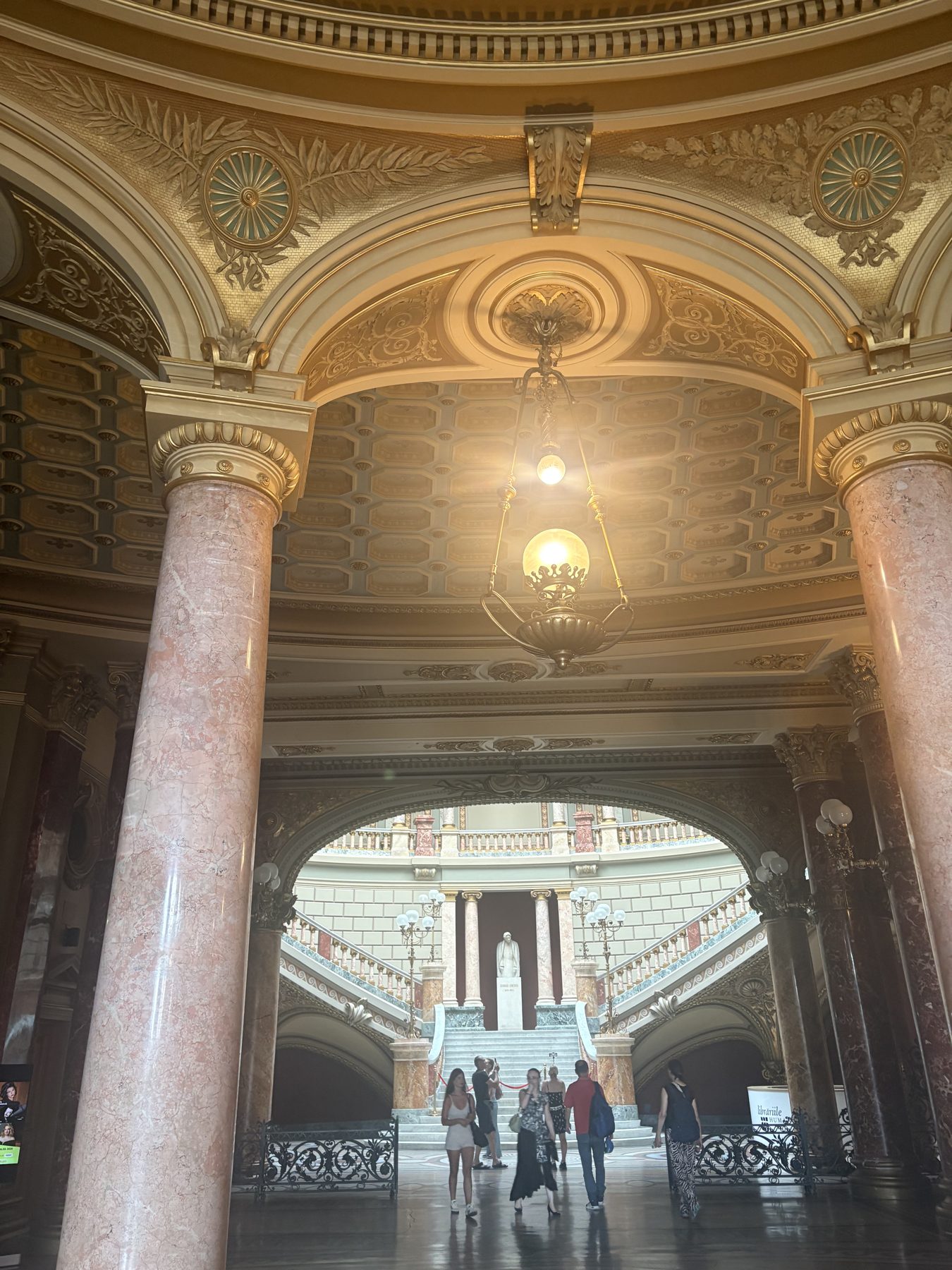 A painted and gilded arcade ceiling with a chandelier