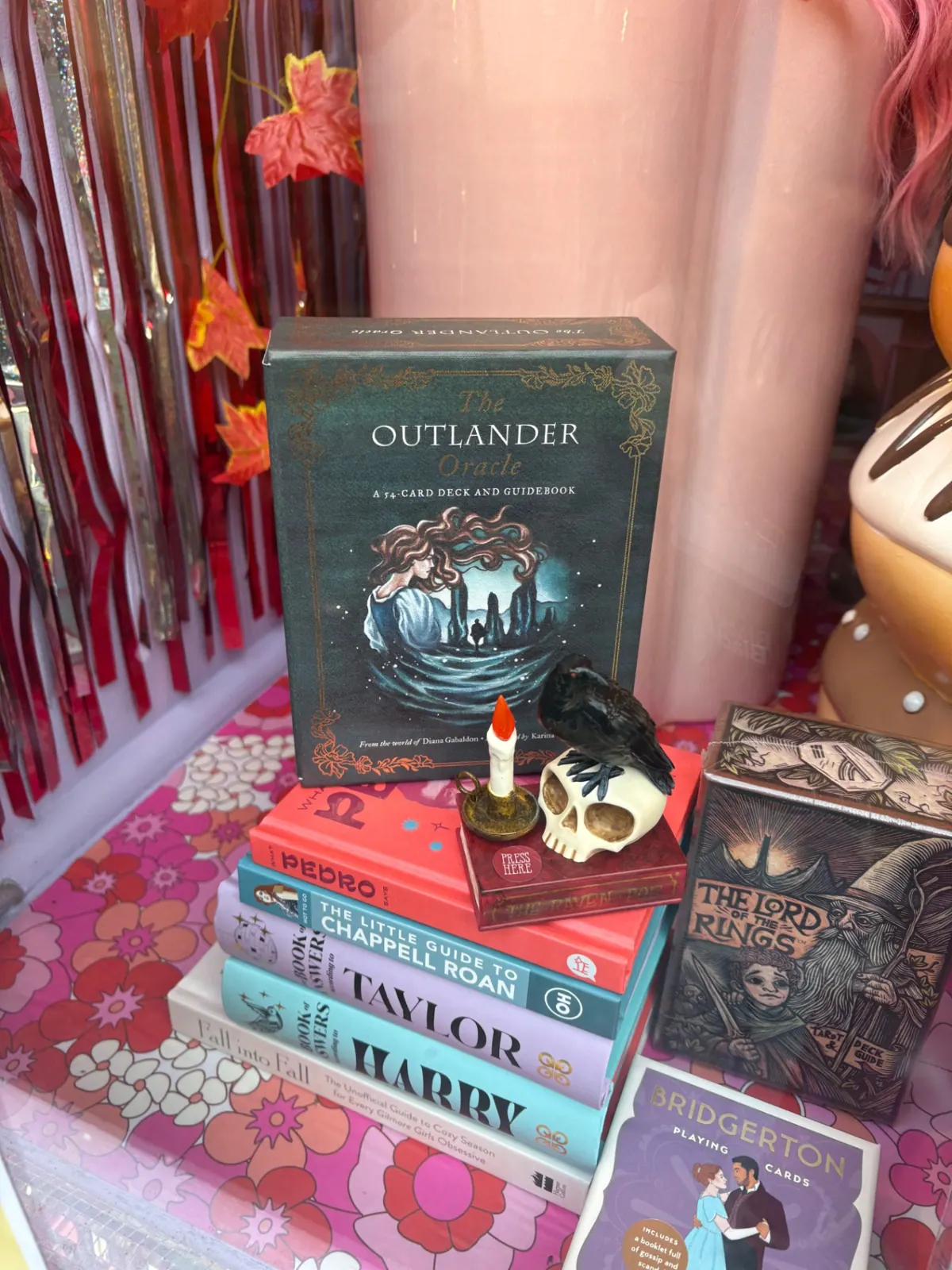 An Outlander oracle deck in a shop window with a candle and raven skull