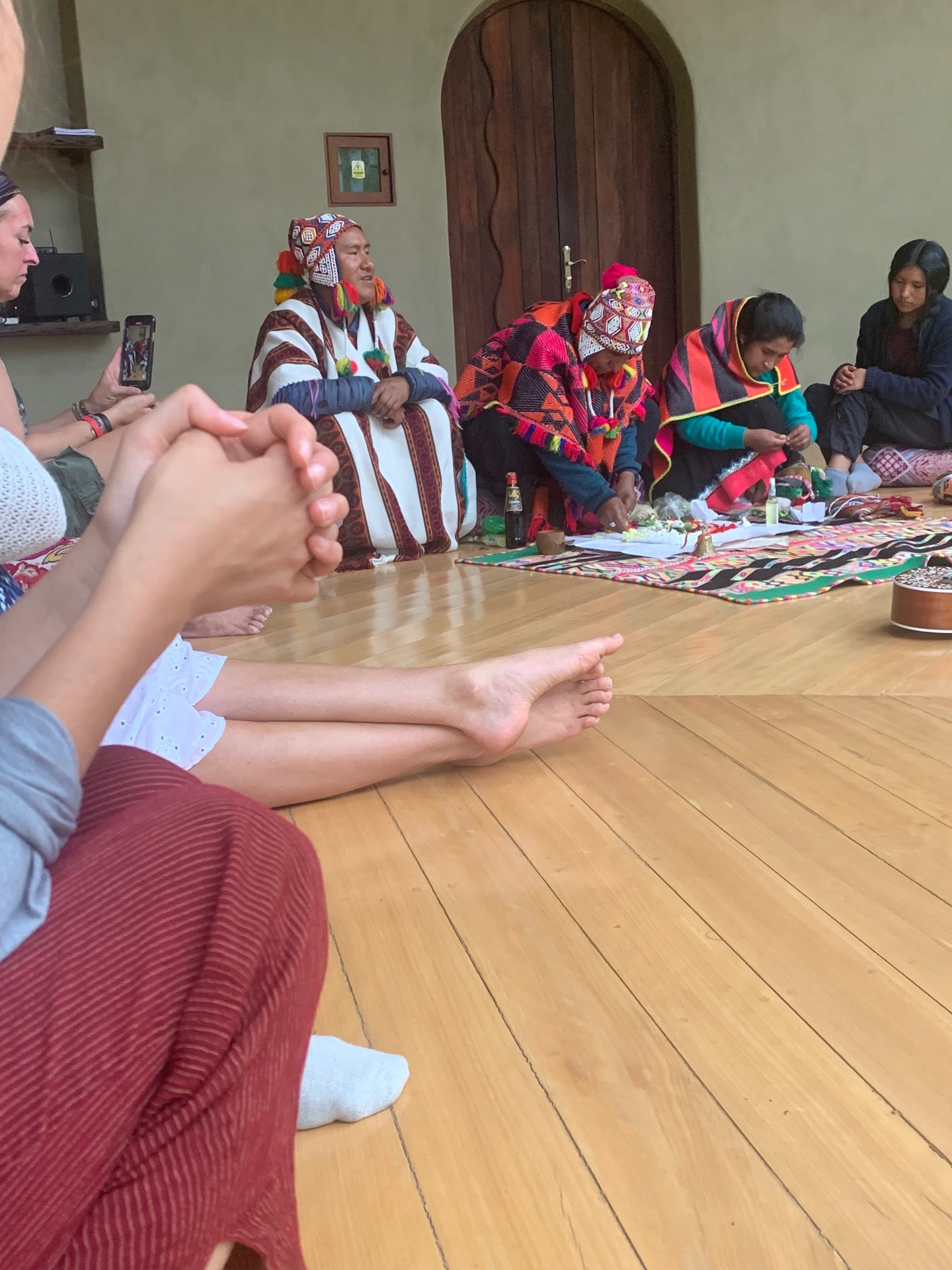 Q'ero elders in woven ponchos leading a despacho ceremony on the floor