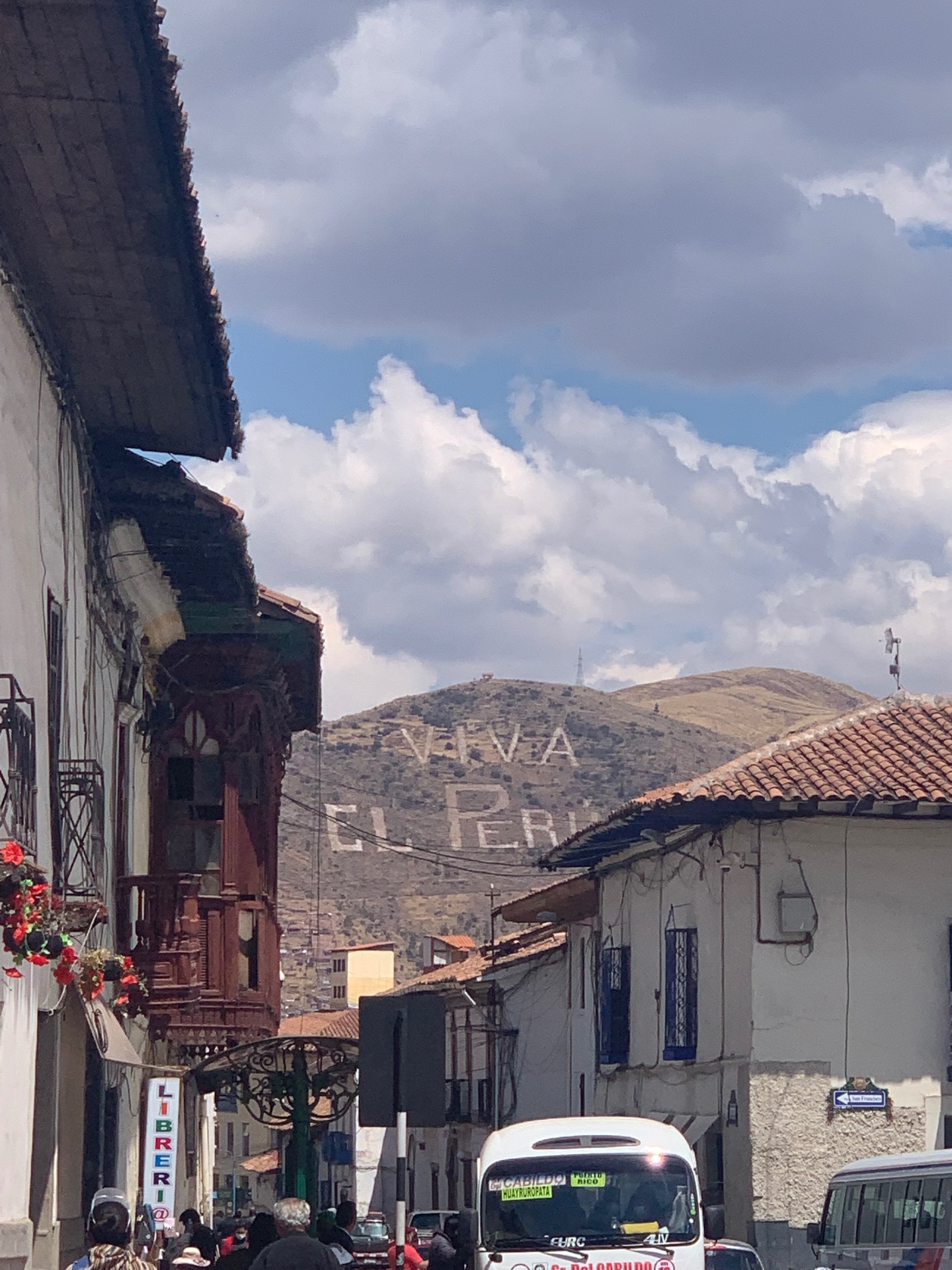 Cusco street with carved wooden balconies and VIVA EL PERU on the hillside