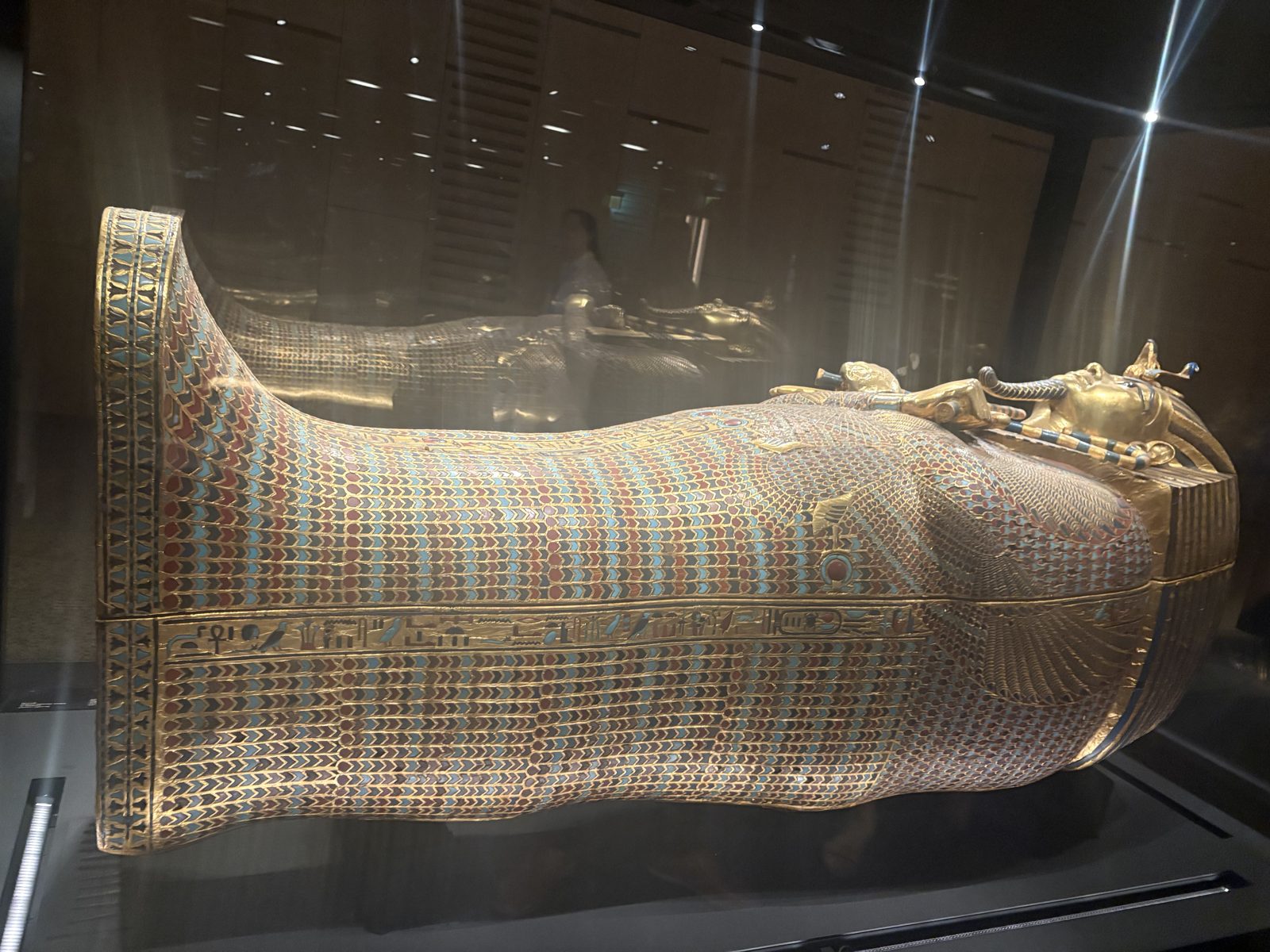 A gilded and inlaid ancient Egyptian coffin in a display case