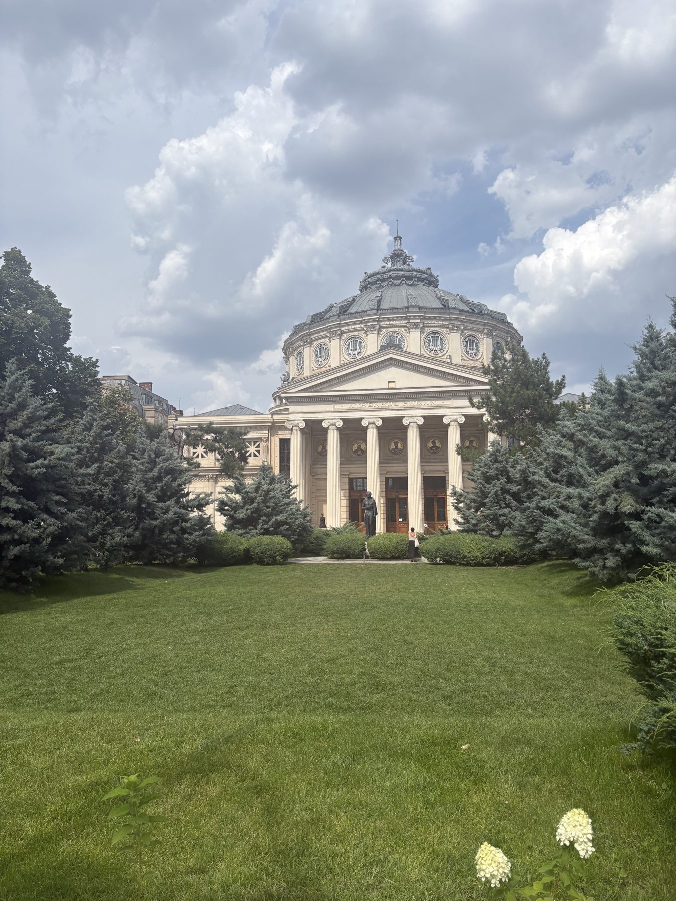 A domed neoclassical building across a green lawn in Bucharest